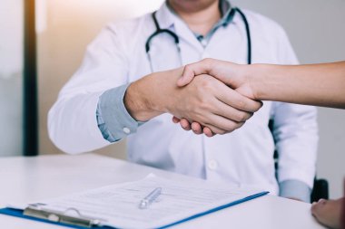 Doktor klinikteki yaşlı hastayla el sıkışıyor..