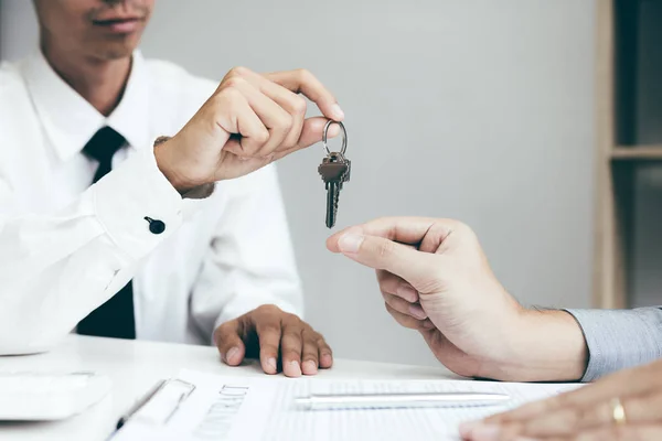 Крупним планом рука домашніх агентів роздає ключі до нового будинку бу — стокове фото
