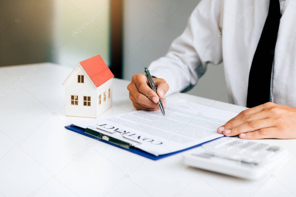 Asian man signing paper contract agreement for house with model 