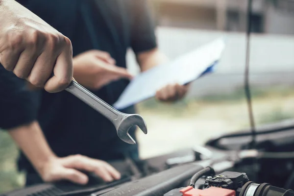 Car mechanic is holding a wrench ready to check the engine and m — Stock Photo, Image