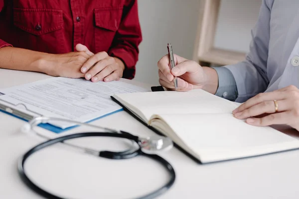 Médico mano celebración pluma escritura paciente historia lista en bloc de notas — Foto de Stock