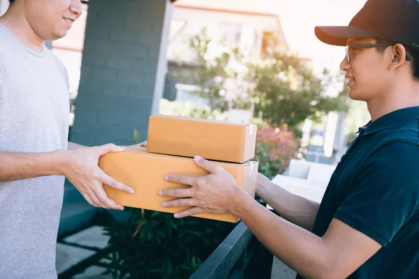 Asiatischer Mann erhält ein Paket von einem Zusteller zu Hause. — Stockfoto