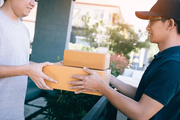 Asiático recibiendo un paquete de un repartidor en casa . — Foto de Stock