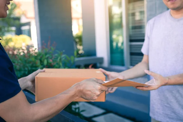 Joven asiático hombre sonriendo mientras la entrega de una caja de cartón a la — Foto de Stock