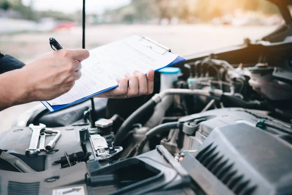 Asian car mechanic doing a check list and note report on paper c — Stock Photo, Image