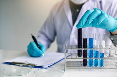 Erkek bilim adamı işçi içinde beyaz ceket çalışma ile test tüpler içinde l