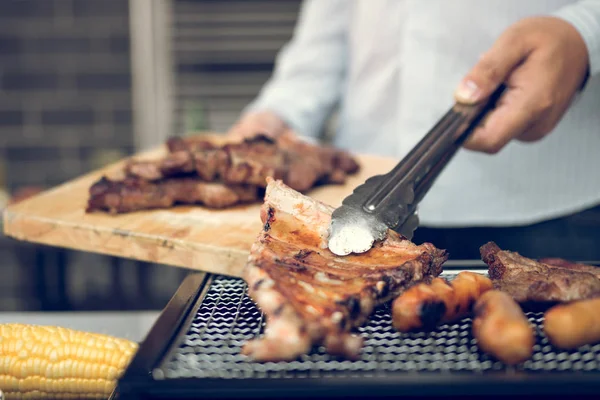 Asiatische Männer kneifen die Schweinerippen auf dem Grill und halten th — Stockfoto