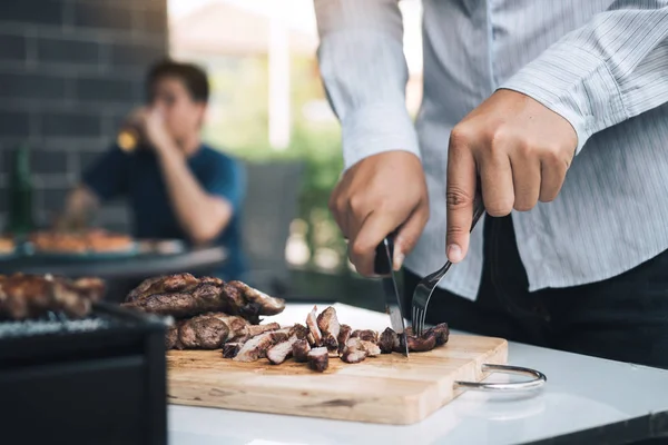 Asiatiska vänner använder en kniv och en gaffel för att skära grillad mig — Stockfoto