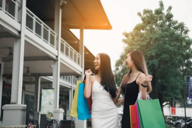 Alışveriş beraber yapmakla alışveriş merkezinde yürüyen mutlu Asya arkadaşlar