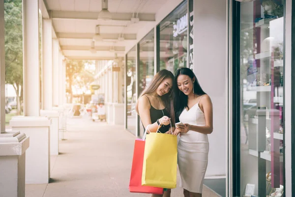 Дві азіатські жінки стоять в магазині спереду з щасливим спостереженням за посмішкою — стокове фото