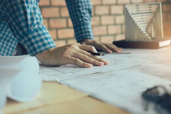 Mano del joven ingeniero dibujando en el plano con el modelo en — Foto de Stock