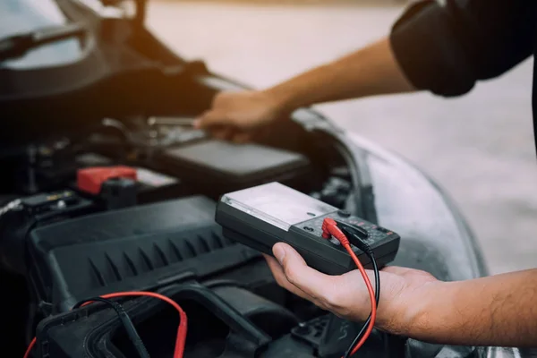 El mecánico del coche está llevando un medidor de batería y comprobando el ge —  Fotos de Stock