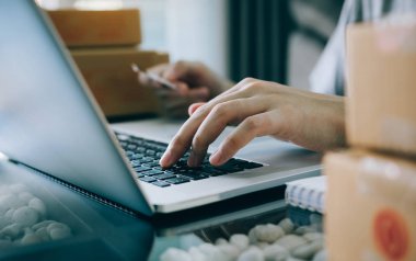 Asya genç bir kredi kartı tutan ve bir dizüstü bilgisayar compute kullanıyor