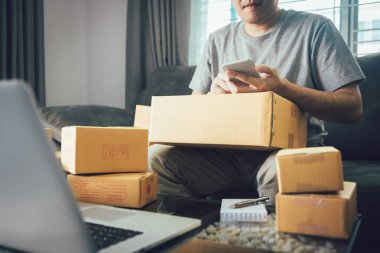 Sevk irsaliyesi evde kontrol etmek için akıllı telefon kullanan Asya genç adam.