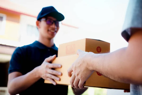 Portador de carga asiático sostiene una caja de cartón con el paquete en el interior — Foto de Stock