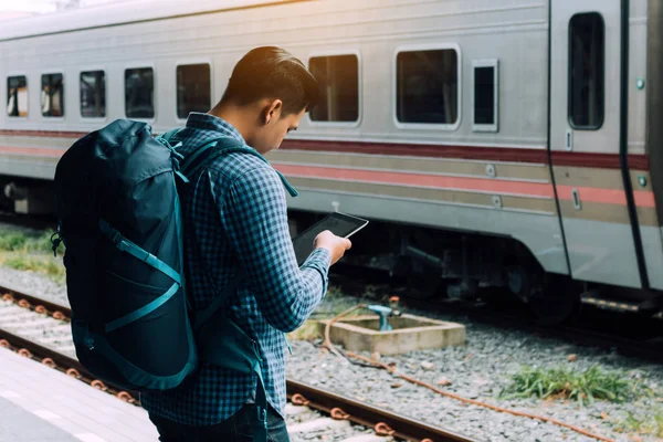 Platformda tren bekleyen asyalı adamın arka görünümü ve tutma sekmesi