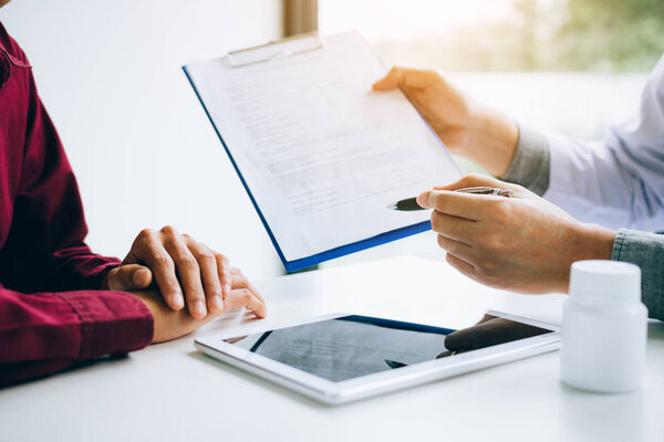 Врач держит ручку и говорит с пациентом о лекарстве
