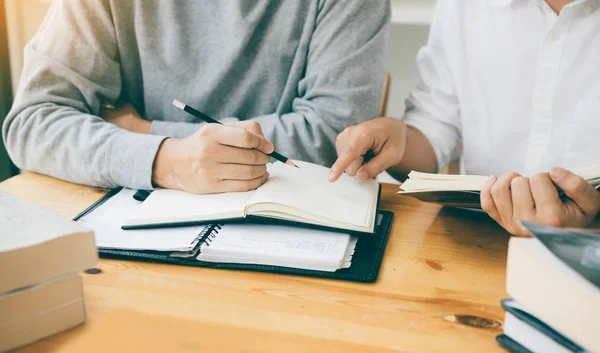 Dos estudiantes leyendo el libro de texto para la prueba juntos en la biblioteca . — Foto de Stock