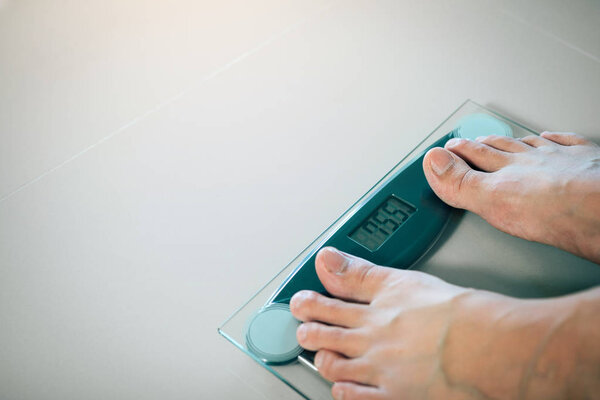 Close up of people feet standing on scale weighing.