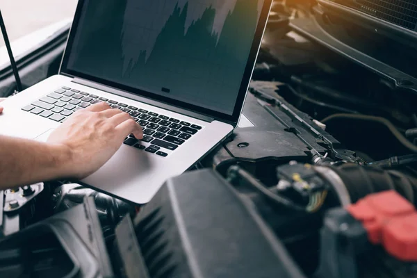 Car repair technicians use laptop computers to measure engine va