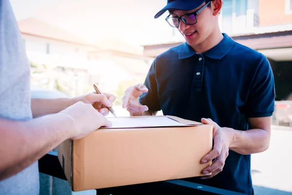 Entrega joven de pie en la puerta de casa y llevando par — Foto de Stock