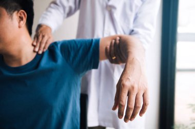 Fizyoterapistler hastanın omzuna baskı yapıyor. Ağrı kontrolü yapıyorlar.