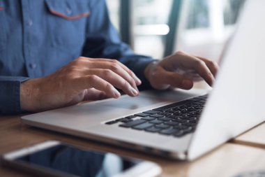 Adamın eli dizüstü bilgisayar klavyesinde yazıyor..