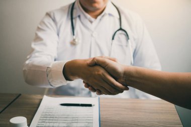 Doktor klinikteki yaşlı hastayla el sıkışıyor..