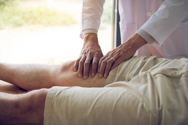 Fyzioterapeuté používají ruce k uchopit pacientovo stehno t — Stock fotografie
