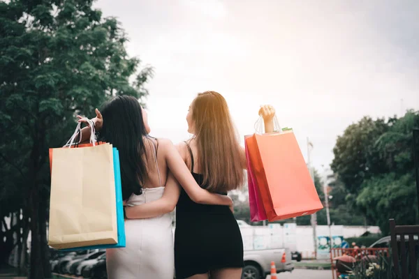 İki güzel asyalı kadın alışveriş çantası tutan arka görüş