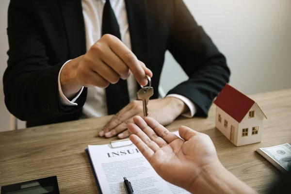 Домашні агенти роздають ключі покупцям будинку, які підписують — стокове фото