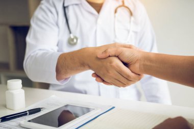 Doktor klinikteki yaşlı hastayla el sıkışıyor..