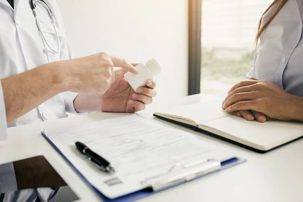 Confiado médico hombre sosteniendo un frasco de la píldora y escribir mientras tal — Foto de Stock