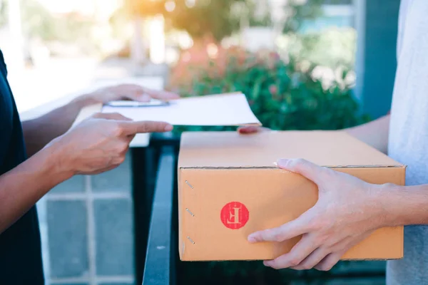 Joven asiático hombre sonriendo mientras la entrega de una caja de cartón a la — Foto de Stock