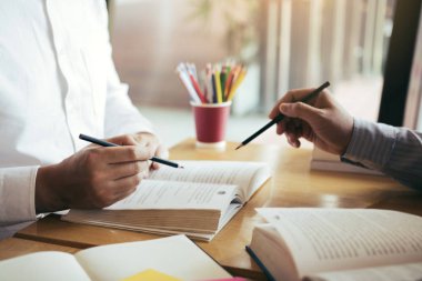 Öğrencilerin kütüphanede ödev hakkında beyin fırtınası için yardımcı oluyor