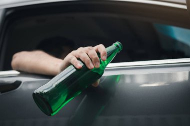 Asya adam sürüş sırasında bir şişe bira arabanın dışında holding