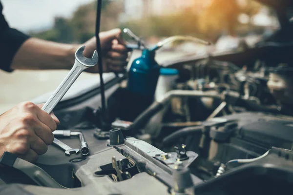 Asijské auto mechanik drží klíč a láhev oleje návnada, přečtěte si — Stock fotografie