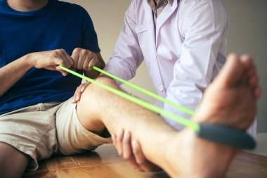 Hasta, bacağını fiziksel olarak uzatan direnç bandı kullanıyor