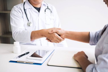Doktor klinikteki yaşlı hastayla el sıkışıyor..