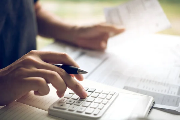 El hombre utiliza calculadoras y documentos que calculan los gastos en el — Foto de Stock