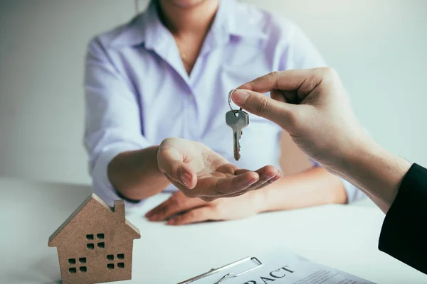 Рука агента з нерухомості передає ключ новим домовласникам в — стокове фото
