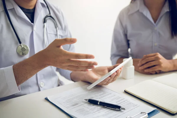 Médico asiático falando o paciente na clínica enquanto usa a mesa — Fotografia de Stock