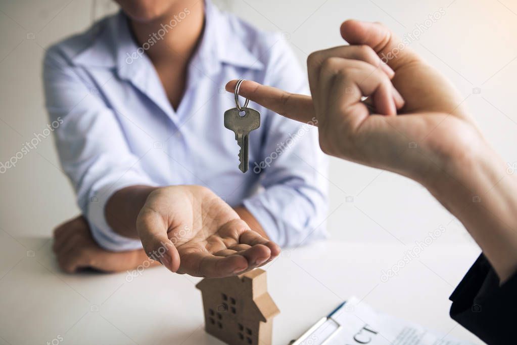 Hand of real estate agent passes the key to new homeowners in of