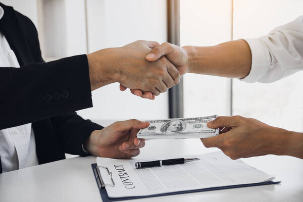 Два корпоративных бизнесмена пожимают друг другу руки, в то время как один человек ставит мон
