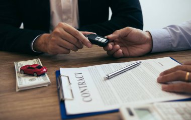 Yeni araba alıcıları arabanın anahtarlarını girin ve sözleşme belgelerini imzalayın.