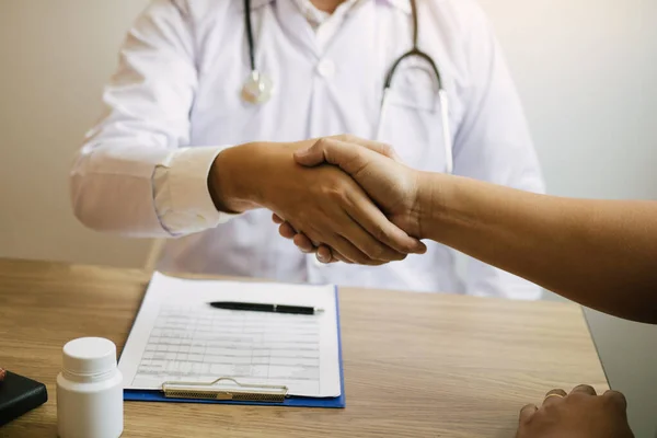 Arzt schüttelt älteren Patienten im Klinikzimmer die Hand. — Stockfoto