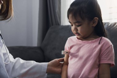 Asyalı kadın doktor evindeki çocukların ateşini ölçmek için termometre kullanıyor..