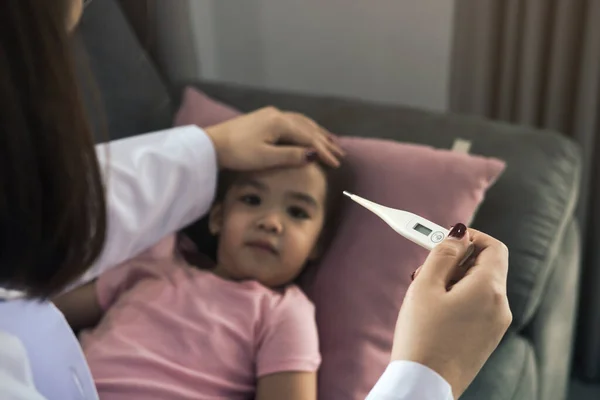 Asian female pediatrician is using a thermometer to measure fever for children