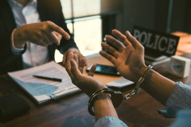Polis memurları suçluların kelepçelerine işaret ettiler ve yolsuzluk suçlamaları hakkında konuştular.
