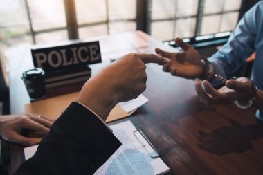 Polis memurları suçluların kelepçelerine işaret ettiler ve yolsuzluk suçlamaları hakkında konuştular.